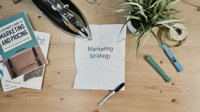 Escritorio con una hoja que dice Marketing Strategy, una pluma y una plancha, simbolizando ordenar la estrategia de marketing de una PyME