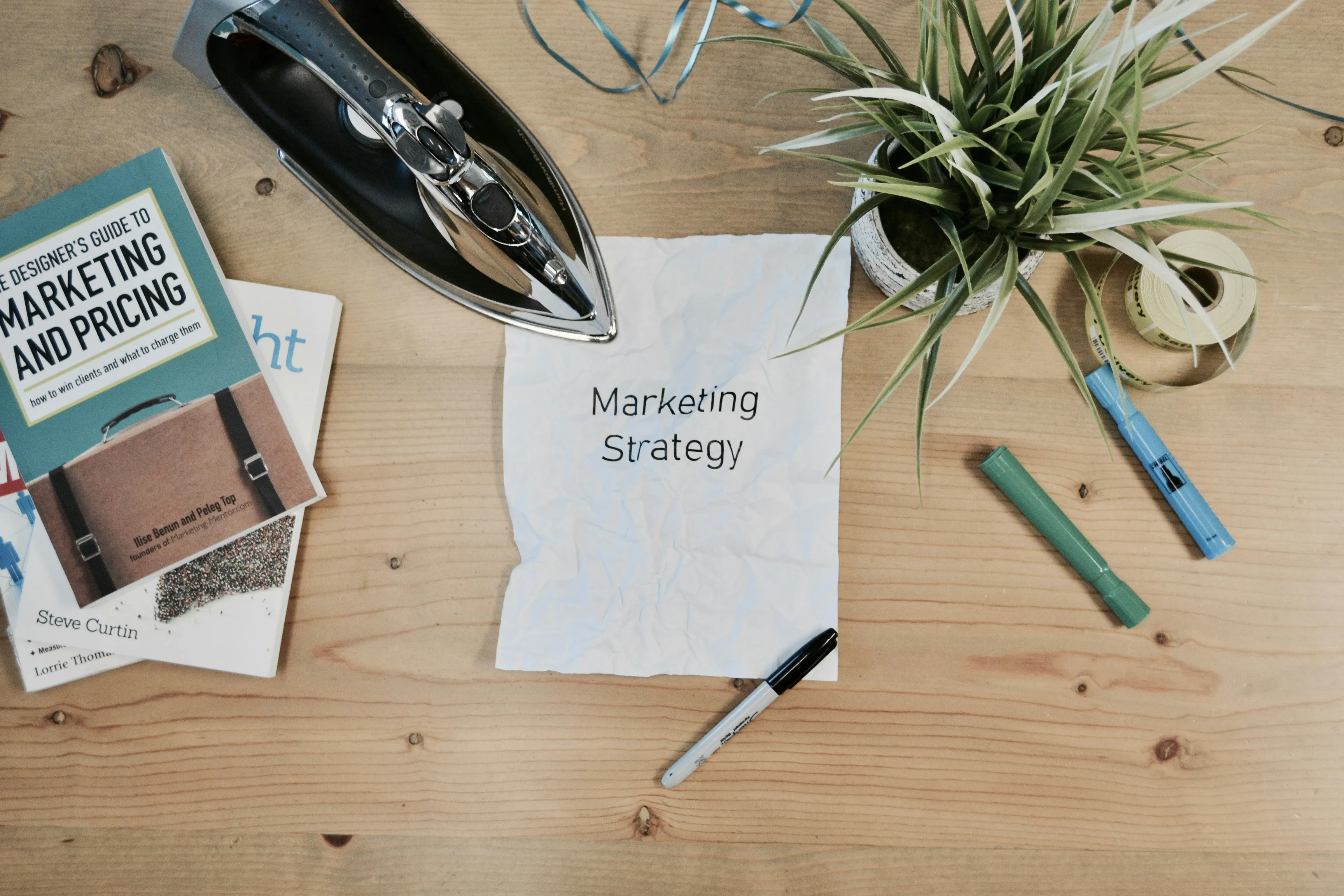 Escritorio con una hoja que dice Marketing Strategy, una pluma y una plancha, simbolizando ordenar la estrategia de marketing de una PyME