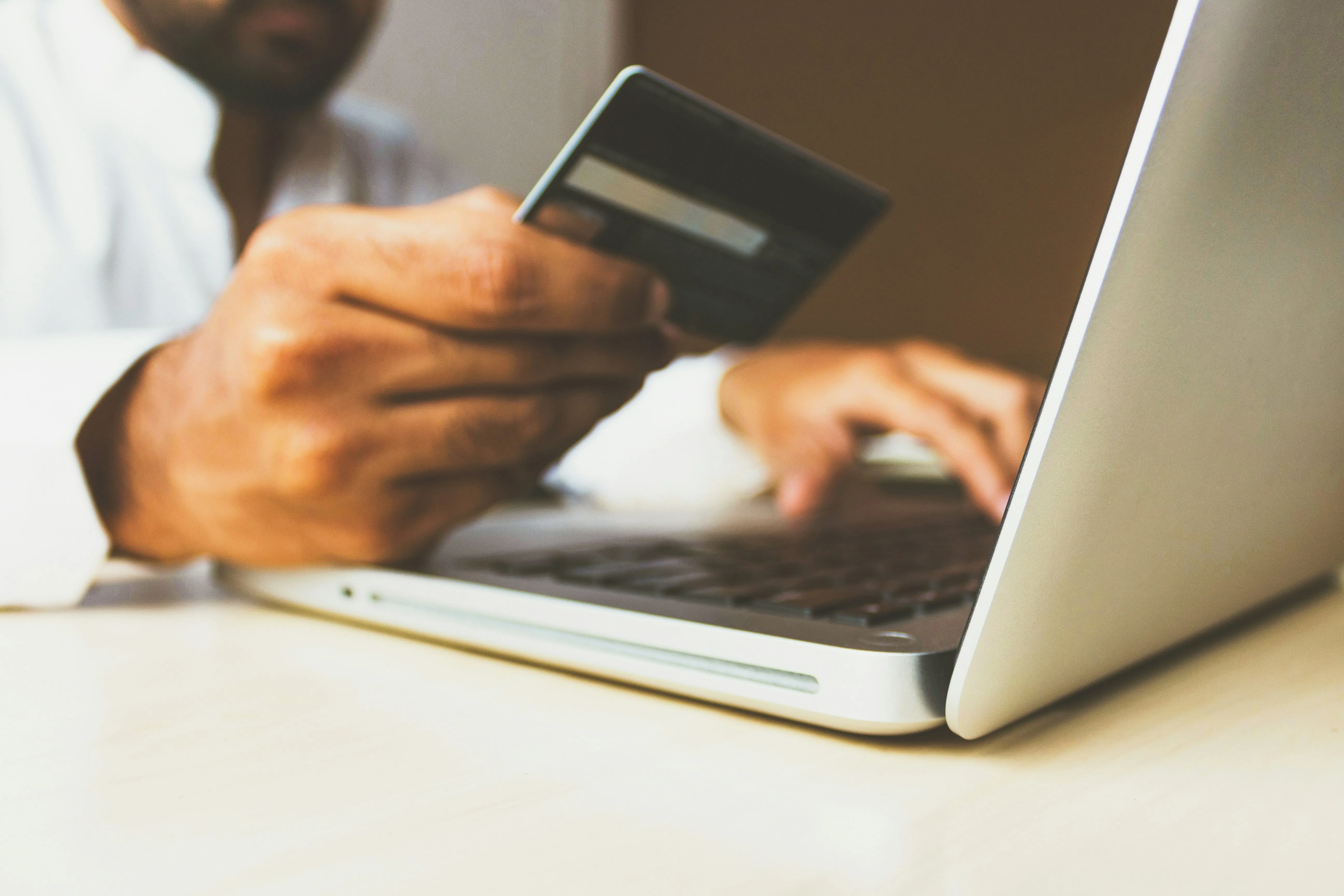 Persona usando una laptop con tarjeta en mano para comprar en una tienda en línea, ejemplo de ecommerce en México