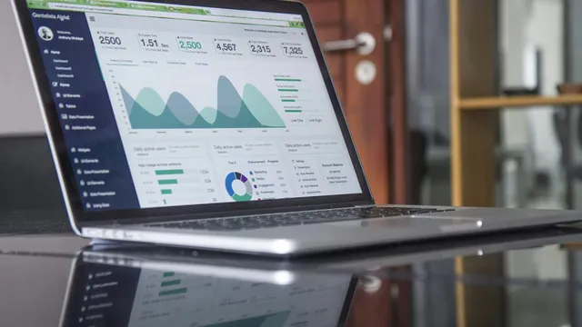 Laptop sobre una mesa de cristal mostrando gráficas y estadísticas de analítica de marketing digital