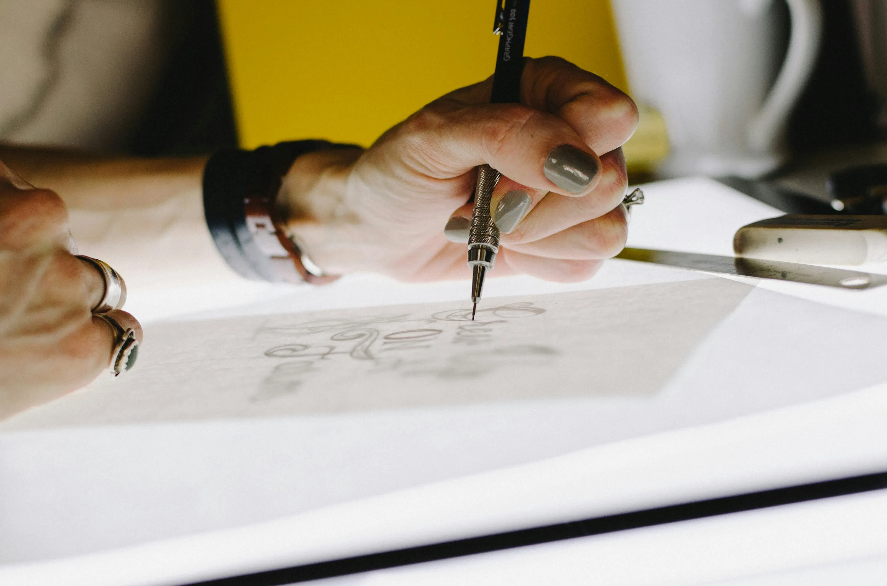 Manos diseñando a lápiz sobre papel albanene el boceto de un logotipo, proceso de diseño de marca