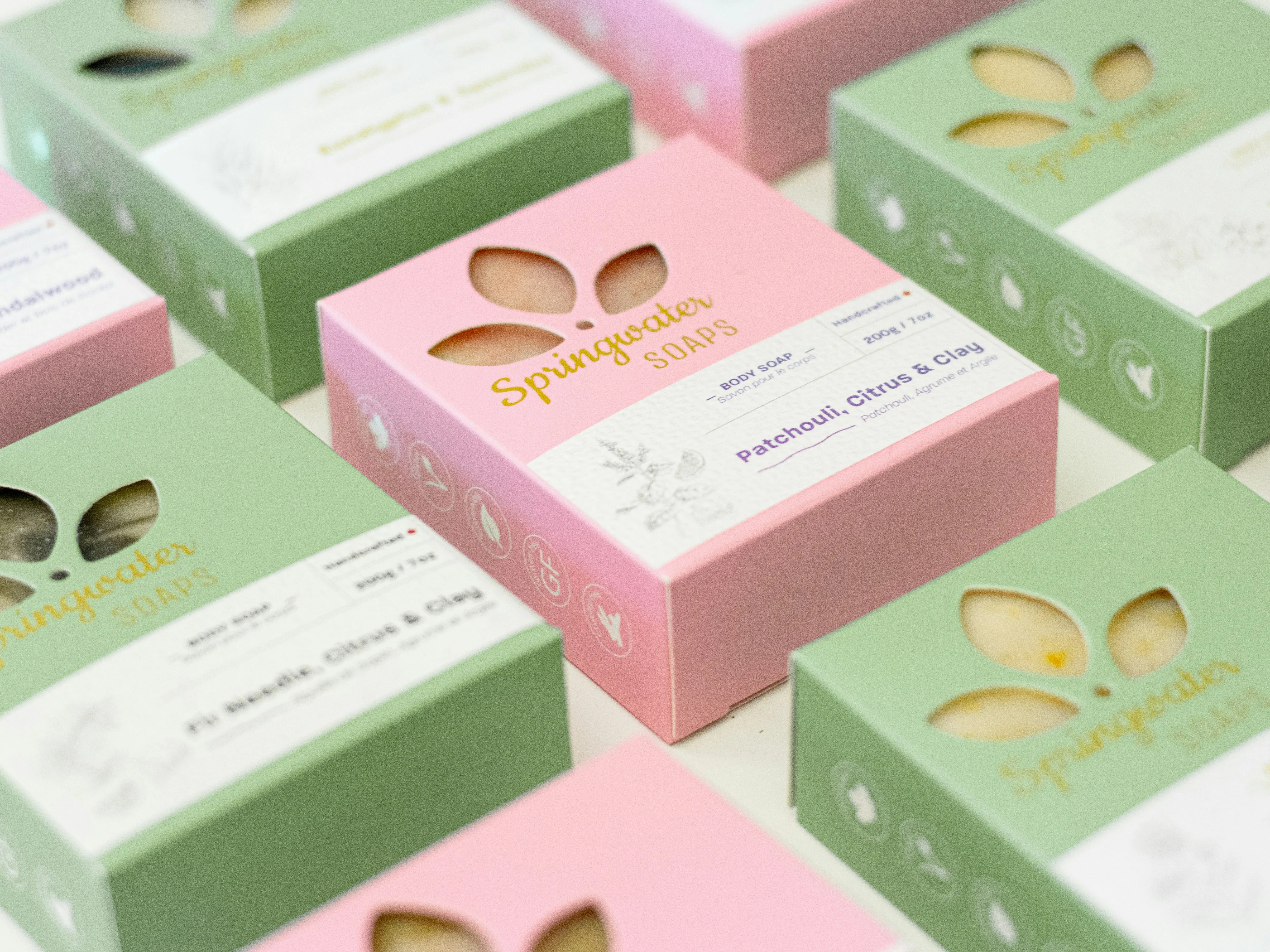 Cajas de cartón en verde y rosa para el empaque de un jabón artesanal, ejemplo de diseño de empaque para un producto pequeño