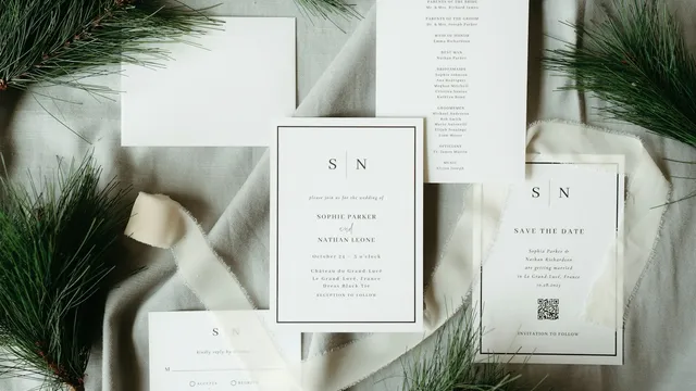 Juego de papelería de boda sobre una superficie clara, con sobres y listones, comparado con las invitaciones digitales