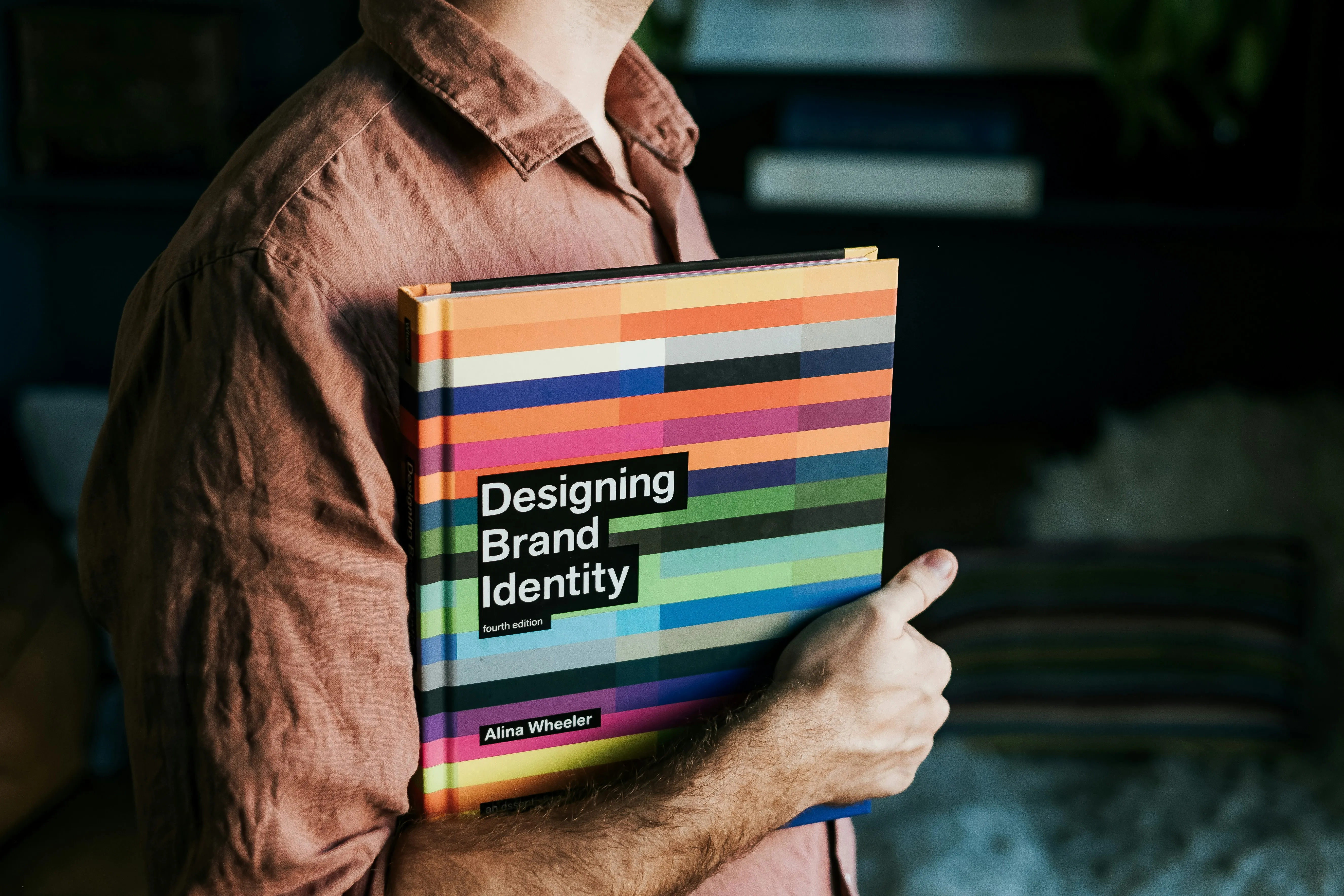 Persona sosteniendo el libro Designing Brand Identity, referencia al manual de marca de una PyME