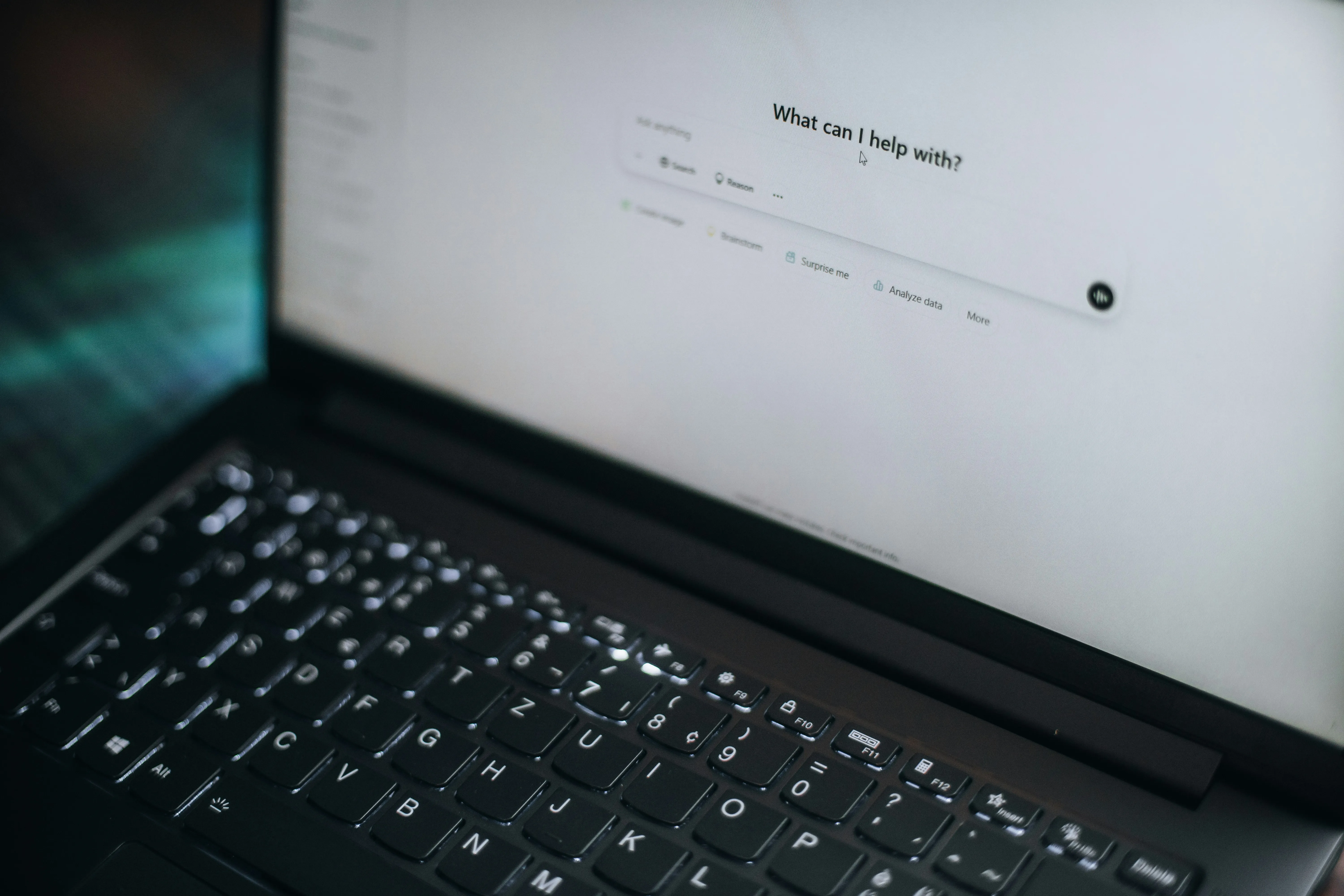 Laptop mostrando un asistente de inteligencia artificial con el mensaje '¿en qué puedo ayudarte?' sobre un escritorio