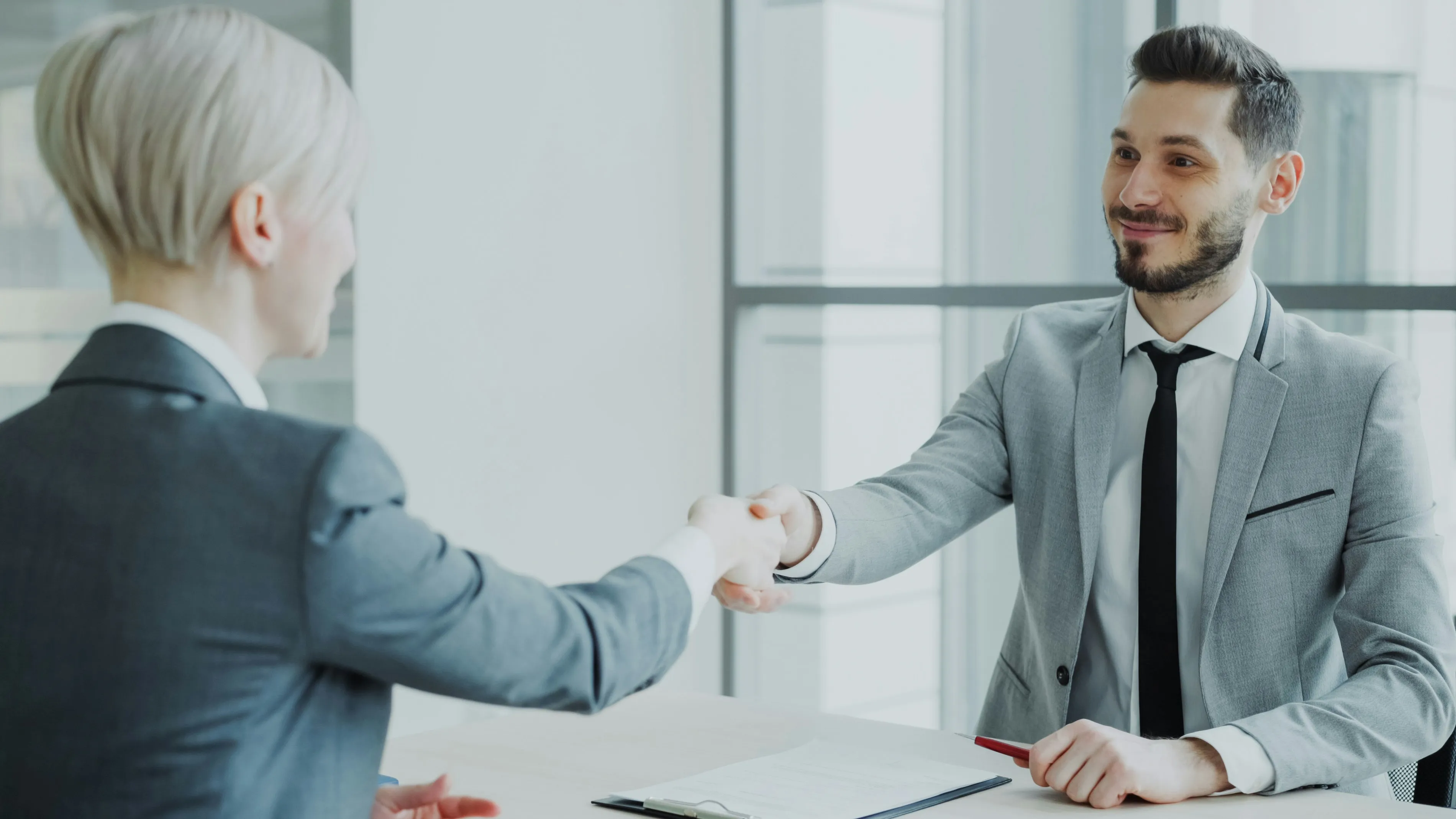 Dos personas dándose la mano sobre una mesa al cerrar un acuerdo, como al contratar una agencia de marketing en Guadalajara