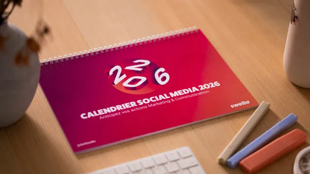 Calendario de escritorio junto a un celular y notas, listo para planear el contenido de redes sociales de un negocio