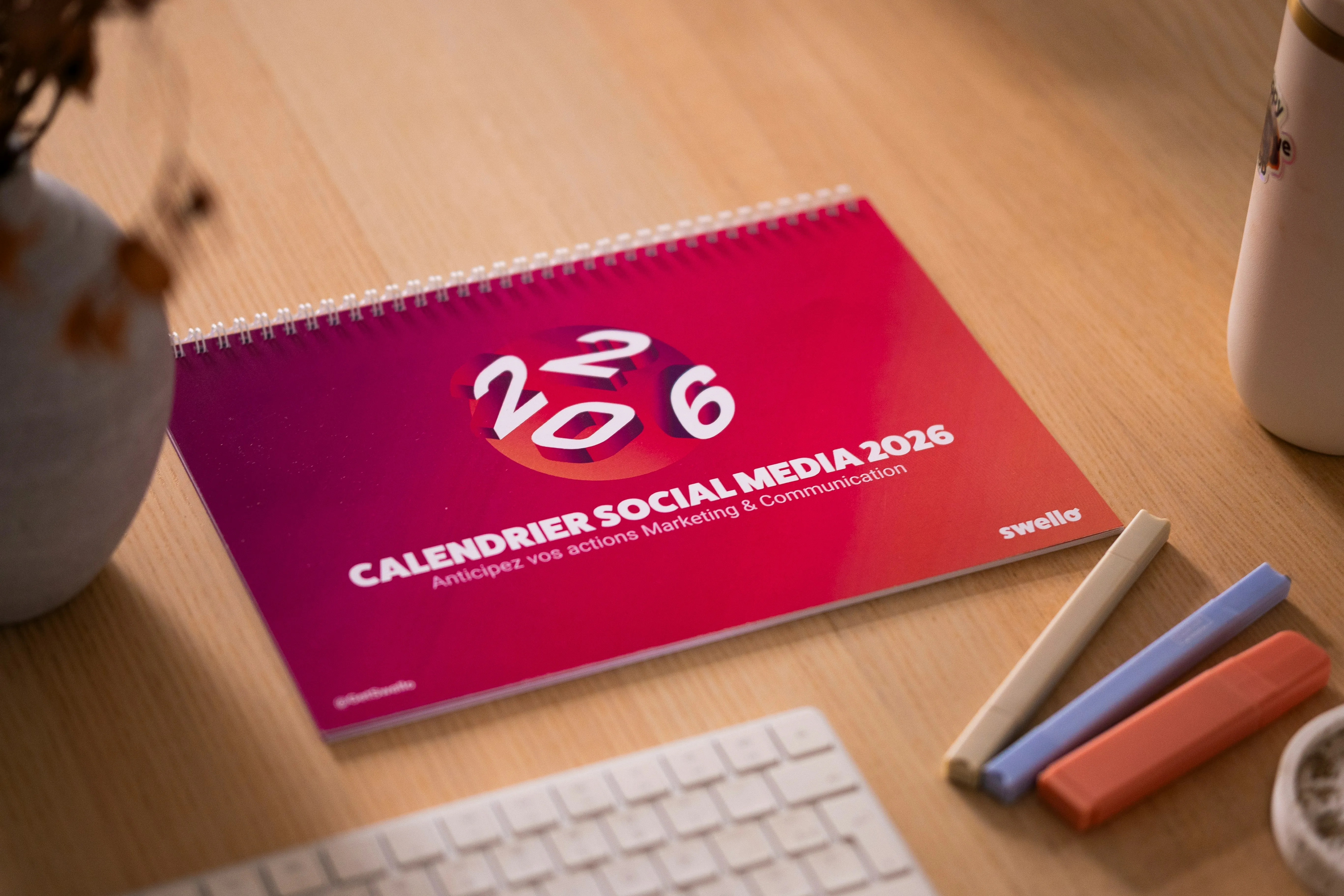 Calendario de escritorio junto a un celular y notas, listo para planear el contenido de redes sociales de un negocio