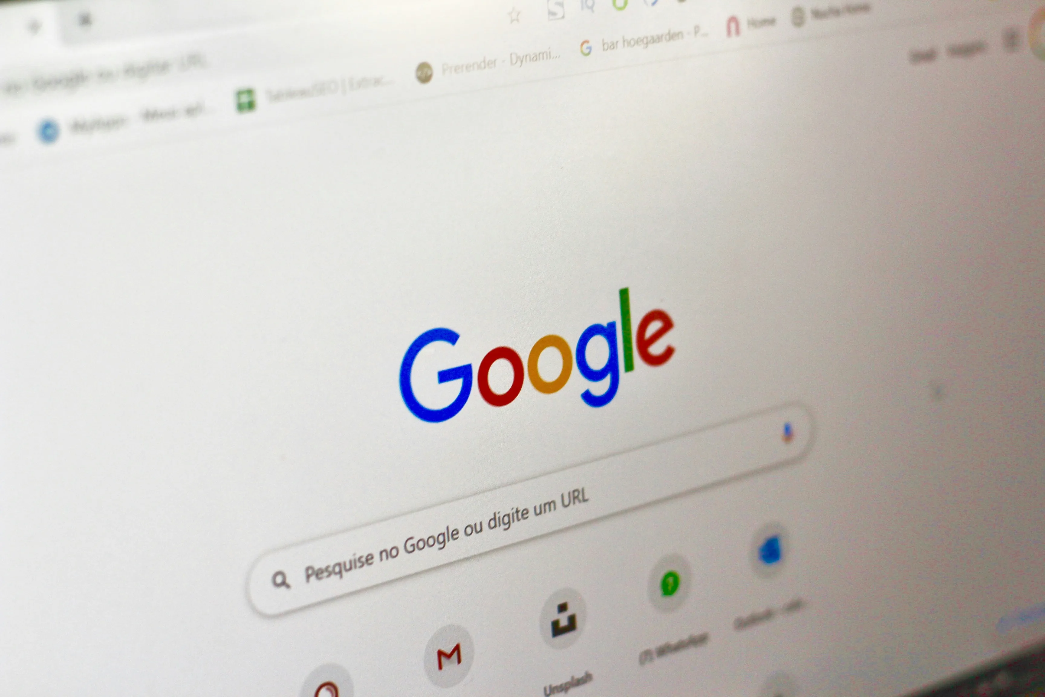Monitor de computadora mostrando la página de búsqueda de Google, sobre un escritorio de trabajo