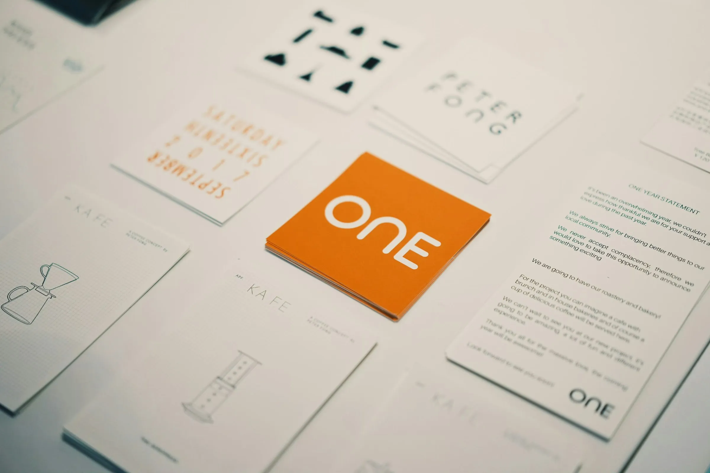 Tarjetas de marca con un logotipo naranja rodeadas de otras tarjetas de color sobre una mesa, ejemplo de identidad visual de una PyME