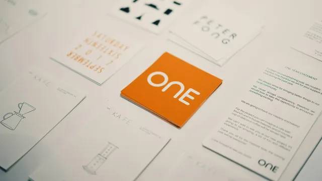 Tarjetas de marca con un logotipo naranja rodeadas de otras tarjetas de color sobre una mesa, ejemplo de identidad visual de una PyME